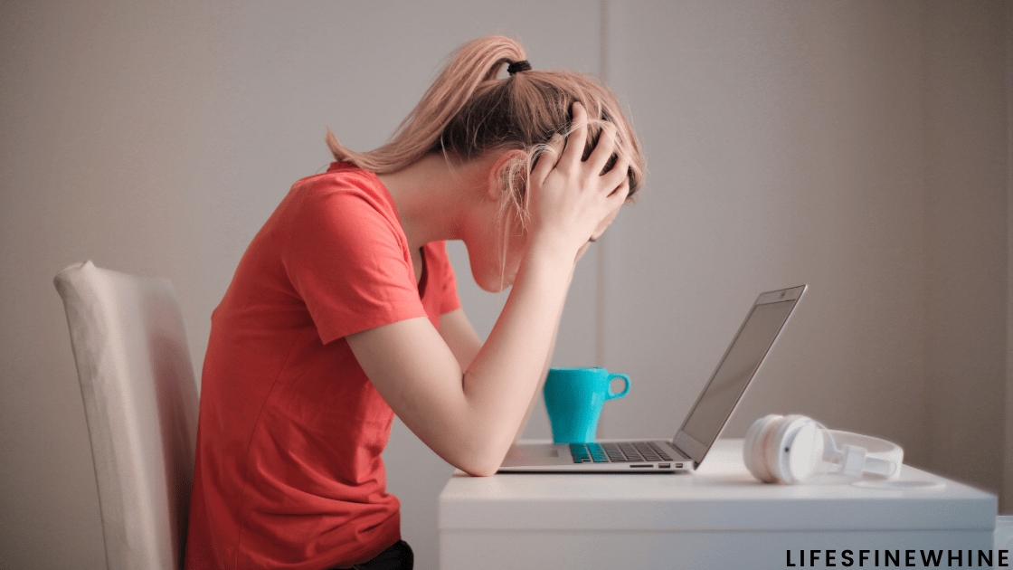 Woman sitting in front of a laptop with her head in her hands | How To Give Your Blog A Makeover