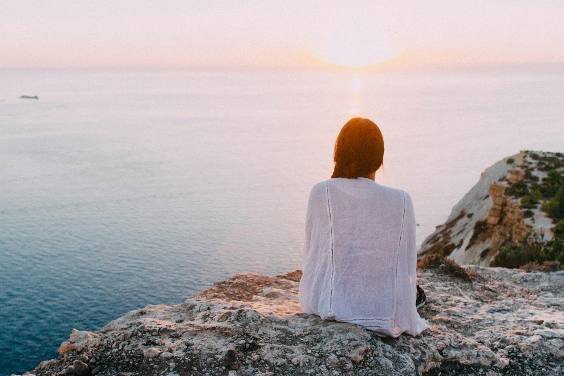 woman sitting on gray rock near body of water | From Struggle to Strength in Mental Health Recovery